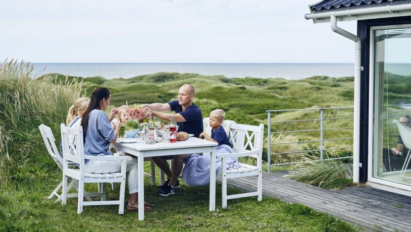 Familie spiser mat utenfor feriehus i Hirtshals