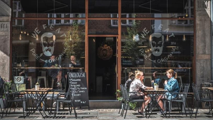 People eating on the street outside vegetarian restaurant We Feat in Aalborg, Denmark 