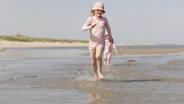 Een meisje loopt door de zee in Noord-Jutland, Denemarken