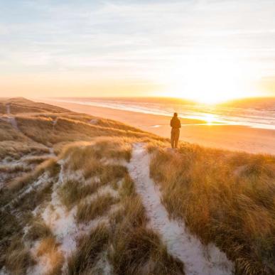 Woman standing at beach in Vesterhavet, sunset